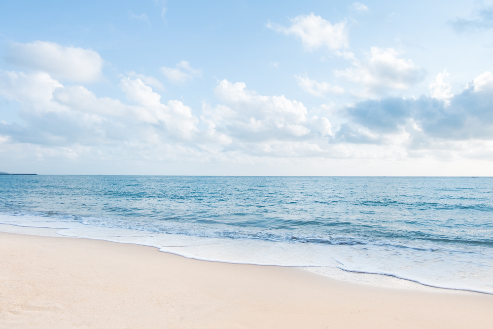 美丽的白色沙滩海浪和清澈的蓝天背景